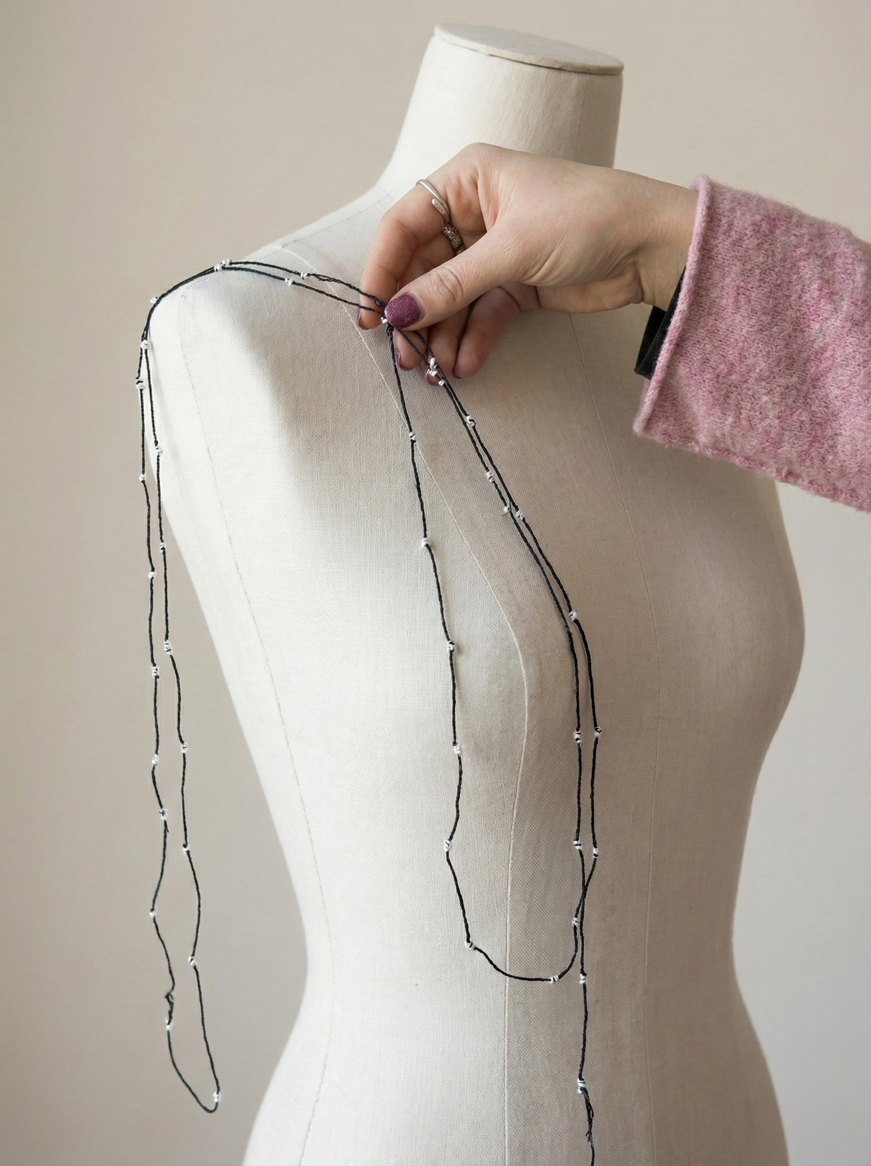 Filato sottile con micro-perle disposto su busto sartoriale